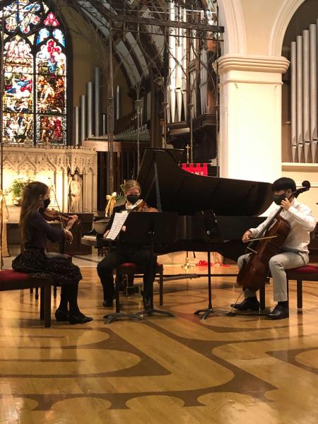 three string musicians sit in front of a grand piano