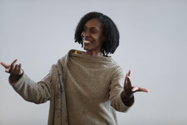 a smiling woman wearing a sweater gestures with her hands as she tells a story