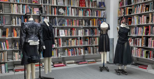 four dress forms in front of two large bookshelves