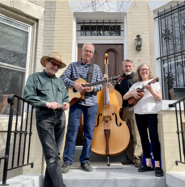 four musicians stand on a front porch with their stringed instruments