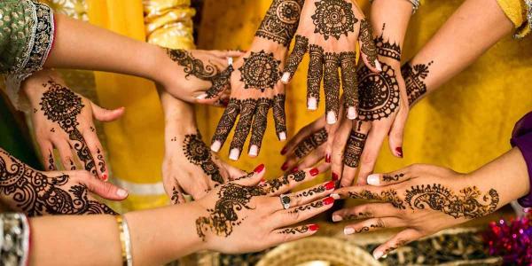 a group of hands adorned with henna reaching towards each