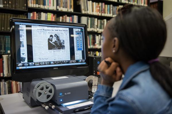 Photo of person looking at newspaper on microfilm