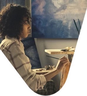 person sits in front on an easel painting