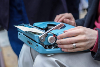 a blue typewriter sits on a person's lap