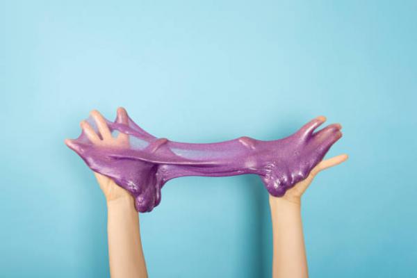 two hands play with purple slime on a blue background