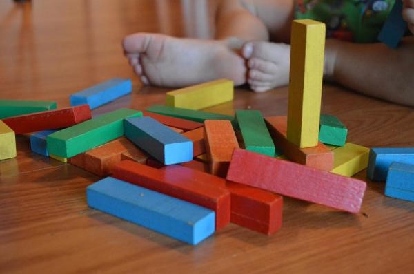 Photograph of colorful building blocks on the floor next to a young child's feet