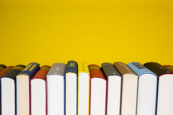 Row of books, spines up with a yellow background 