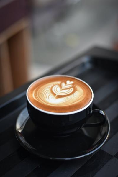 latte in a black mug with saucer