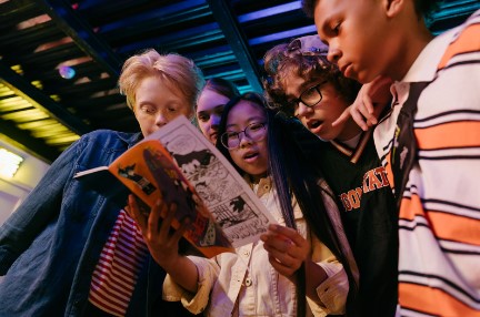 A group of teens reading a book.