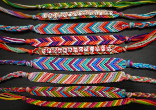Nine friendship bracelets in a rainbow of colors made out of embroidery floss.
