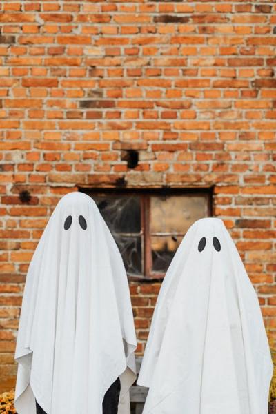 image of two people dressed as ghosts with white sheets and black eyes