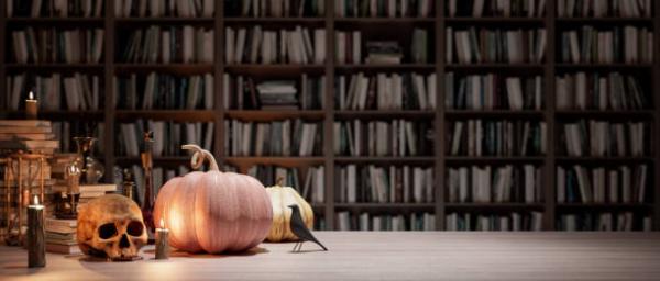 a pumpkin, skull and a bird in front of a large book shelf