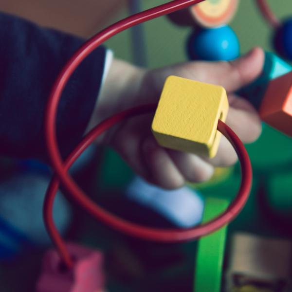 small hand plays with a yellow block on a red wire