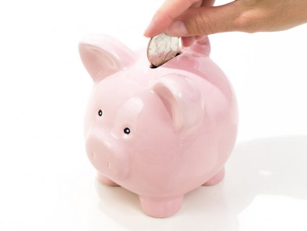 hand putting a coin into a piggy bank