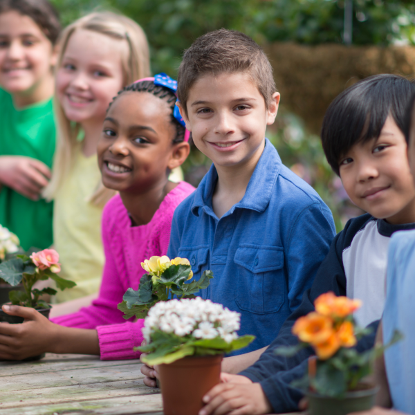 smiling kids holding potted flowers