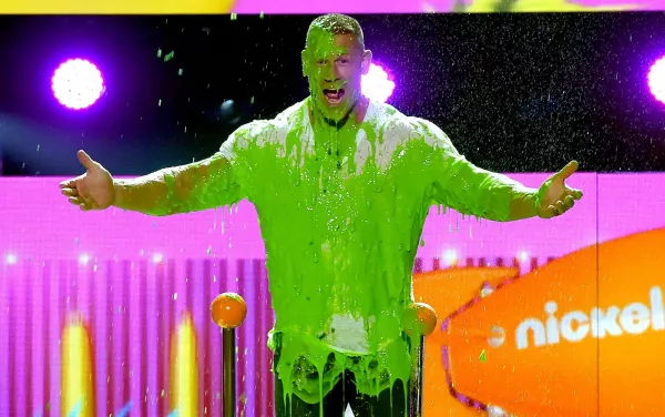 Person covered in green slime in front of a Nickelodeon sign
