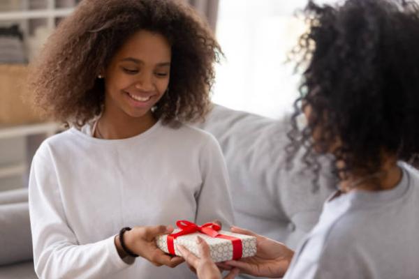 ten handing a gift to another teen